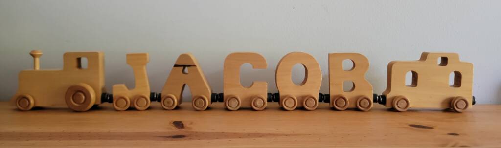Wooden train with individual letters spelling JACOB.