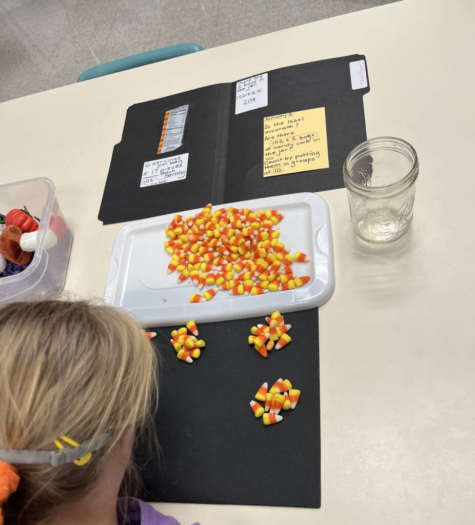 Student doing a filefolder activity that involves candy corn in a jar. She groups them int o10s for skip counting. 