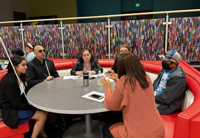 A group of people sitting a table talking to one another
