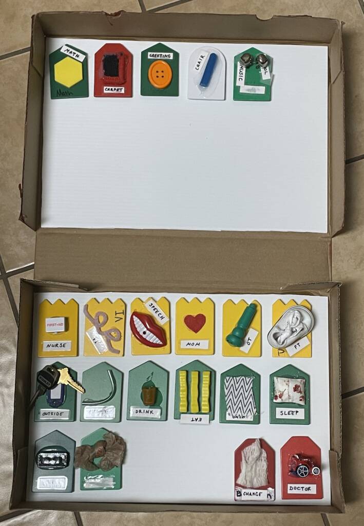 A row on top and a row three rows on the bottom of an opened flip top box containing tactile communication cards.