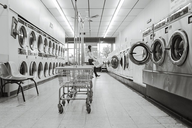 Rows of washers and dryers with a rolling basket in the middle of the room.
