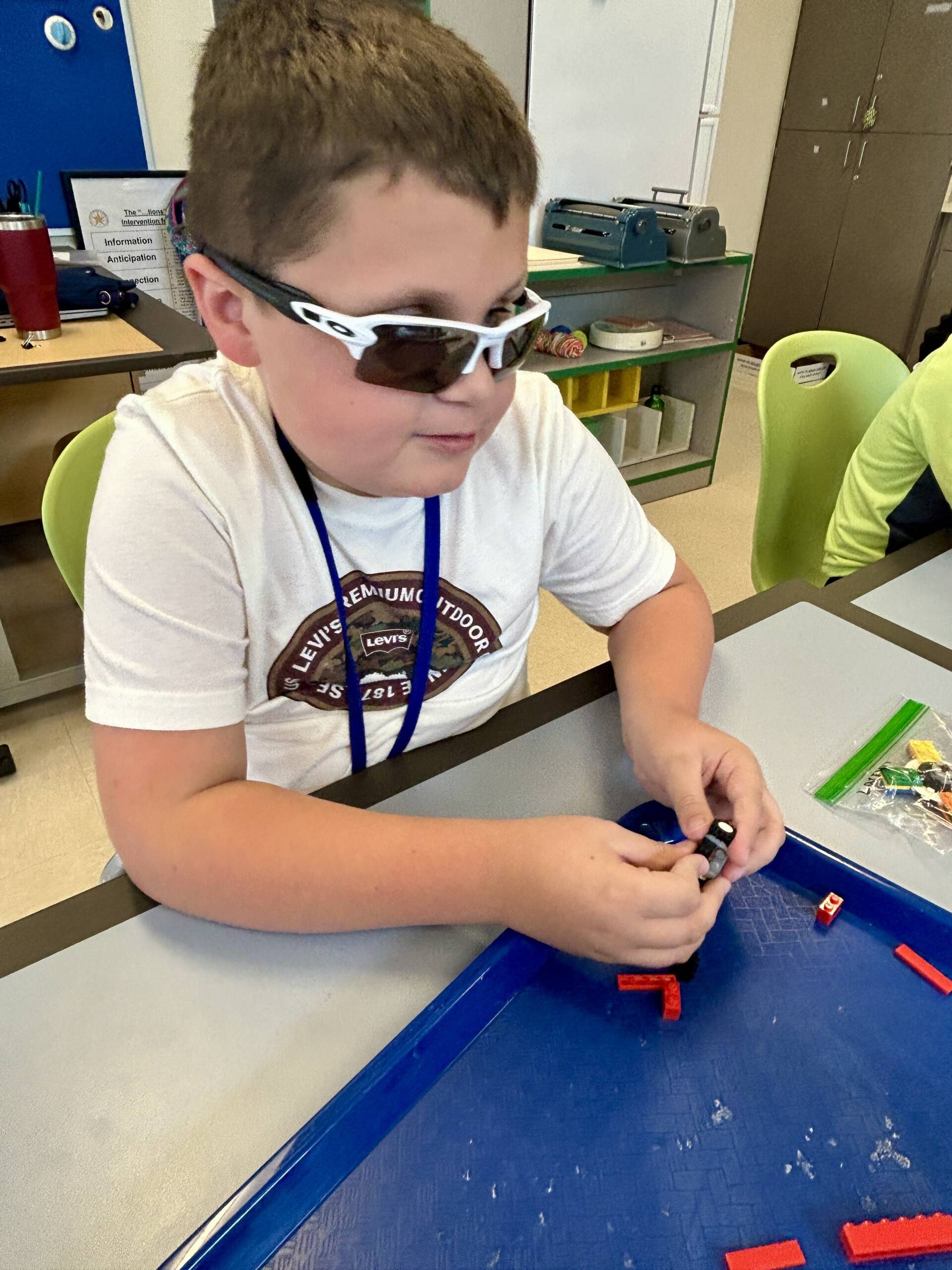 A boy touching legos on a tray