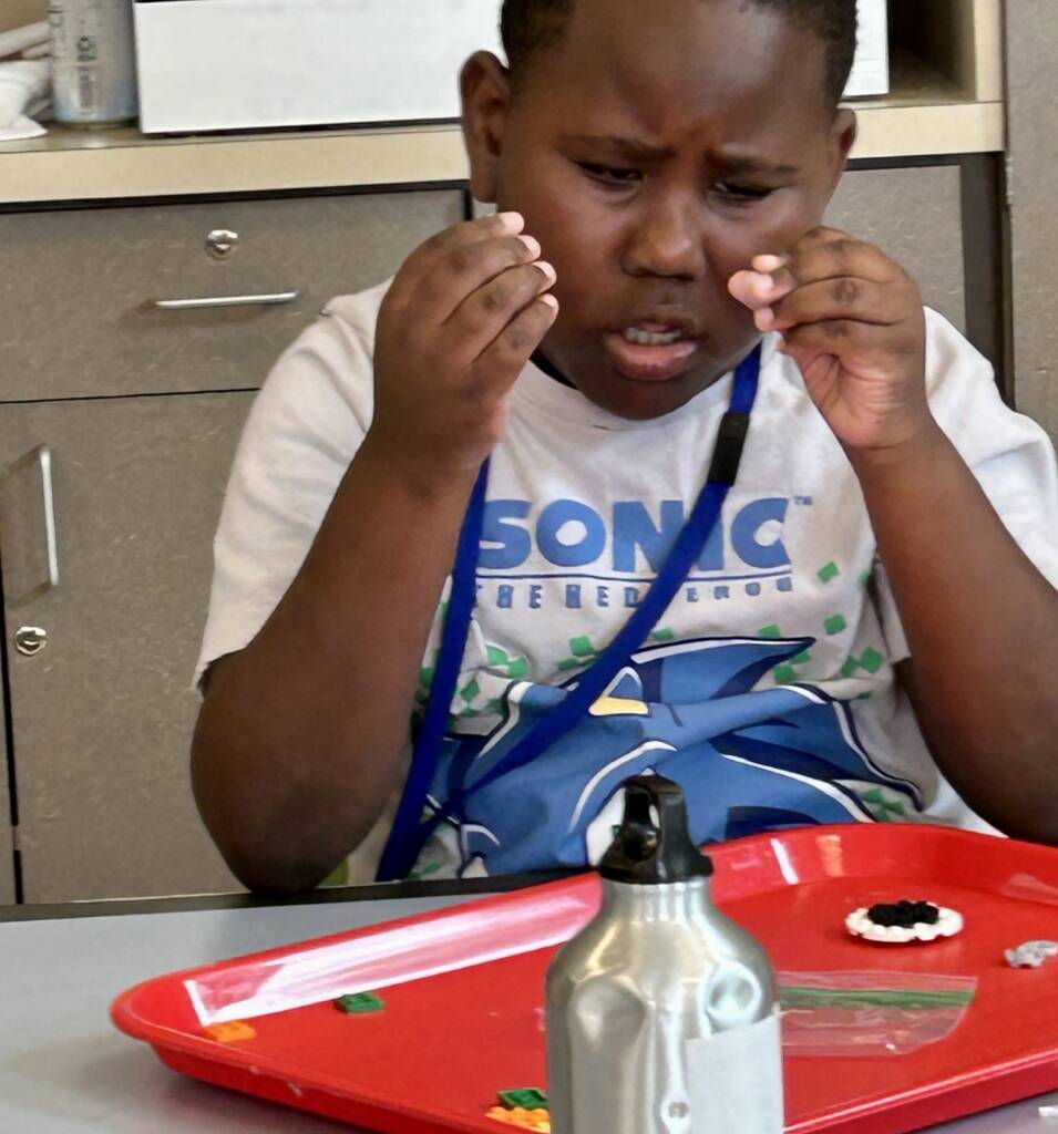 A student touching and looking a individual lego pieces. 