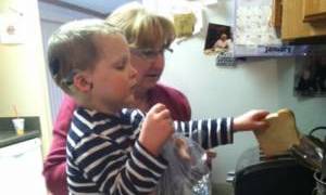 A boy making toast with his teacher
