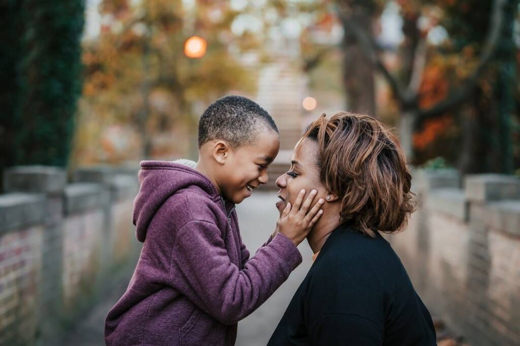 Young son touching his mom's face next to him while outside.