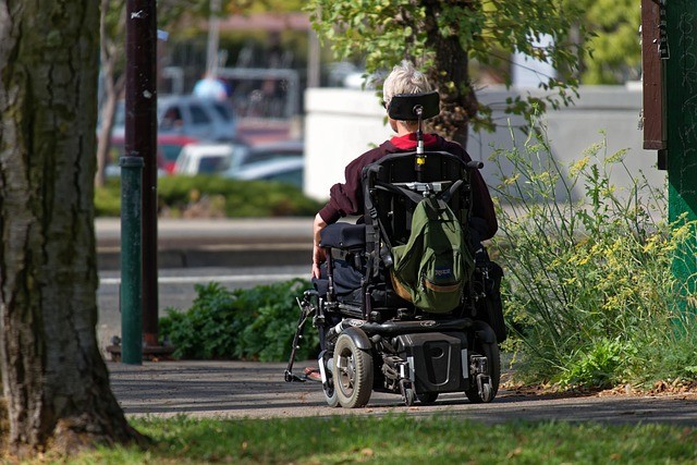 Person outside on the sidewalk in a motorized wheelchair. 