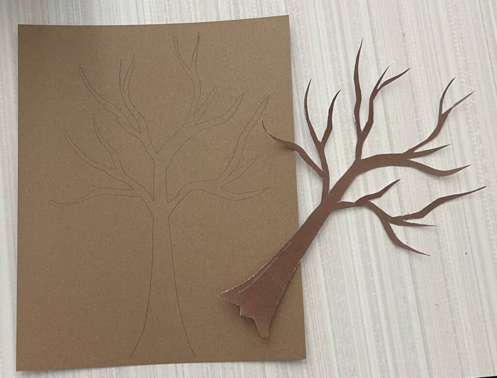 Tracing a bare tree onto a sheet of cardboard. 