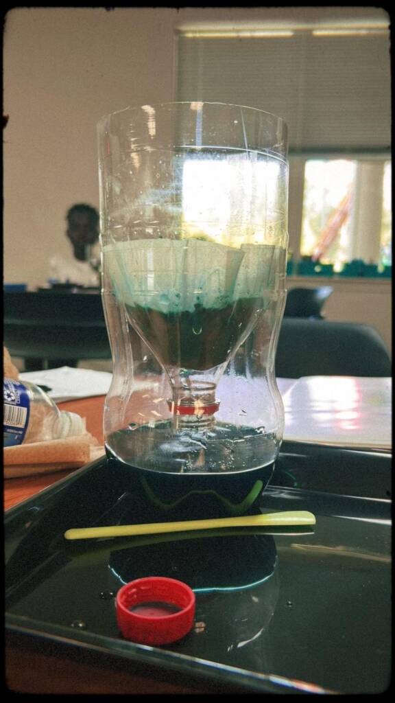 Photo of the soil percolation experimental set-up with colored water filtering through a soil sample. 