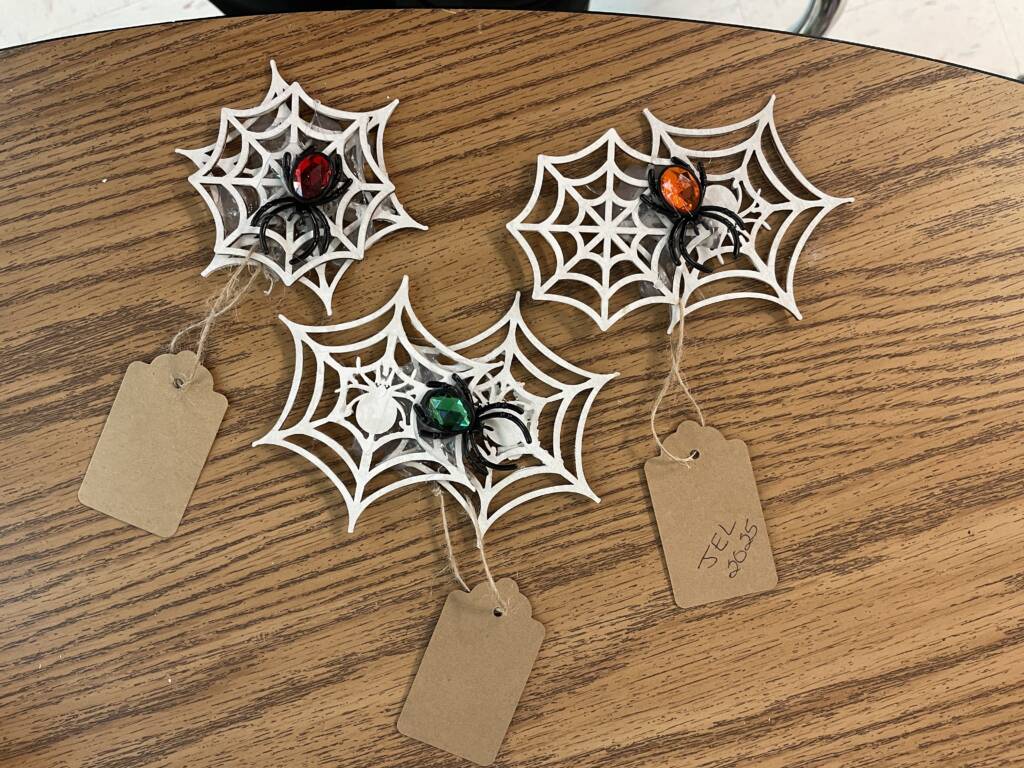 Wooden spider webs with a plastic spider in it.