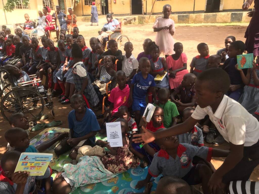 A large group of primary school students from Uganda sitting out front of their school.