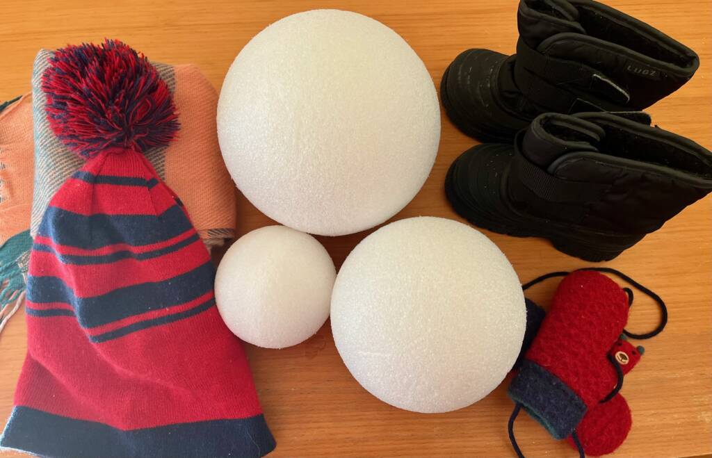 Winter items that include three styrofoam balls, boots, mittens, and a hat. 