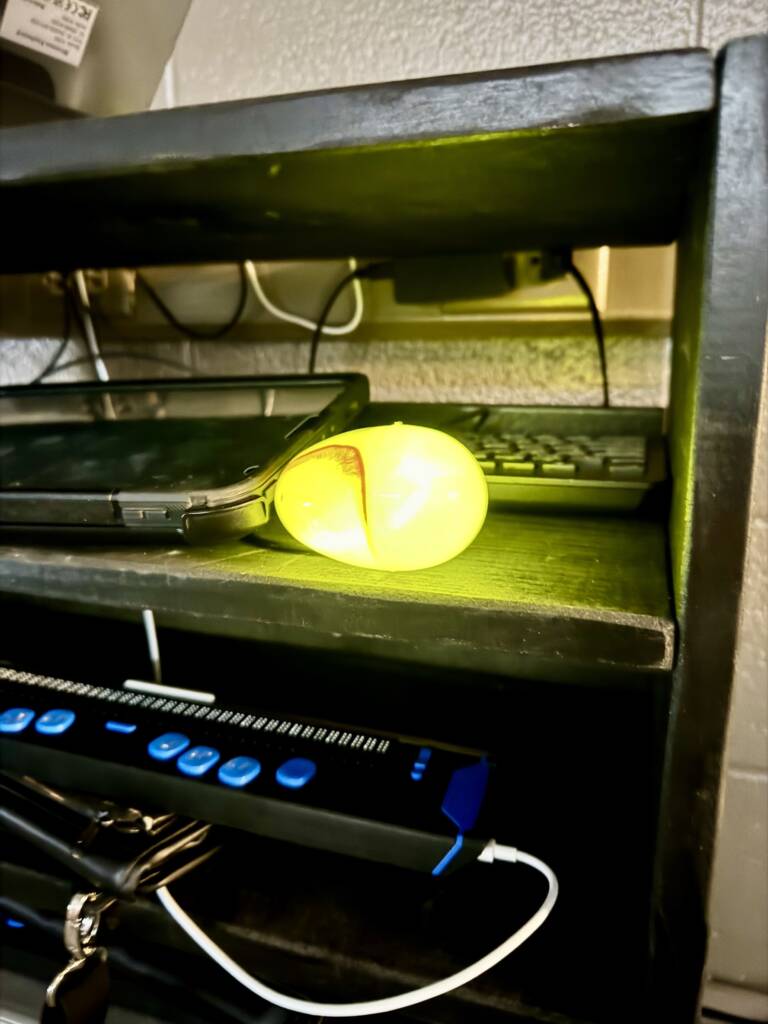 Light up yellow plastic egg on a shelf. 