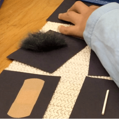 A child examines cards with tactile symbols on a table