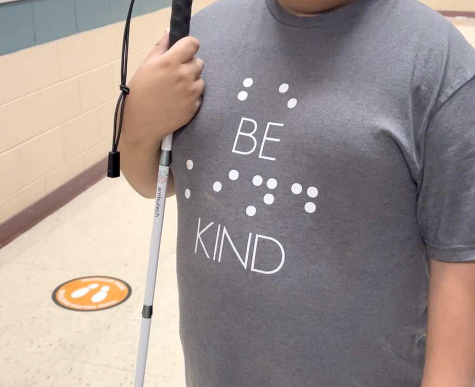 Student holding their cane in a school hallway.