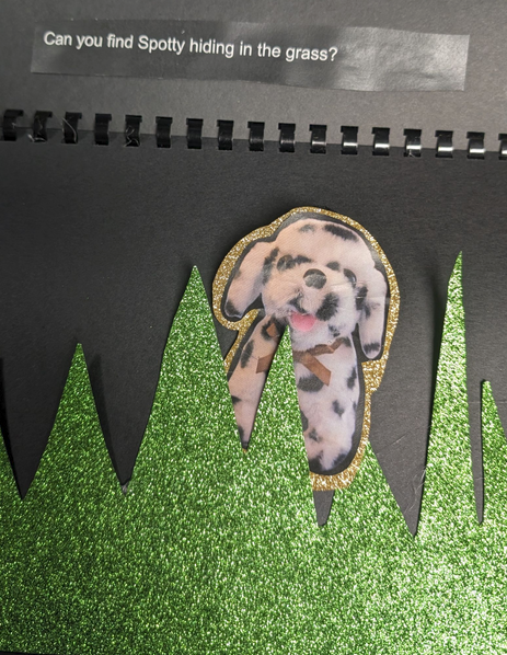 Page of the teacher created book with Spotty the dog behind grass that is textured paper. 