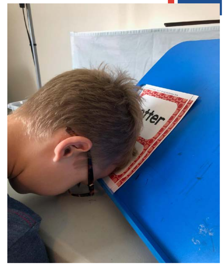 A boy puts his head down on his desk.